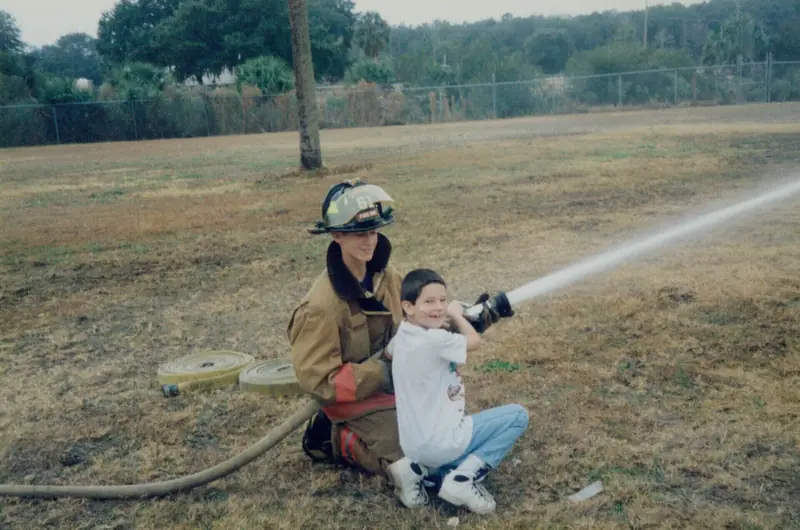 Firefighter helping a child spray a fire hose – School Visits in Orlando, FL